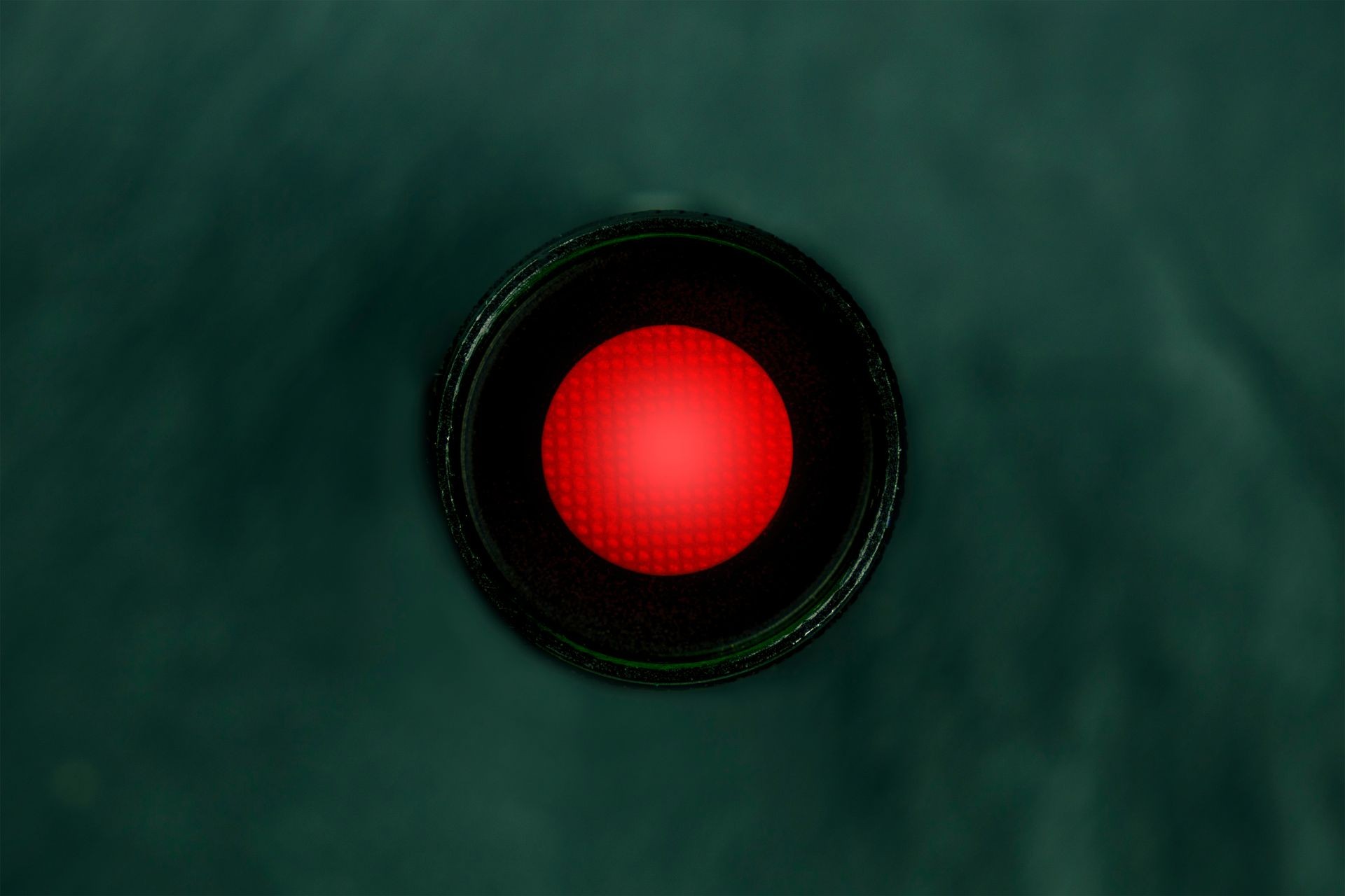 An overhead photo of a vibrant red button, a kill switch on a dark panel with copy space